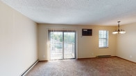 Located at 895 Ohio Pike in Cincinnati, Ohio, this single-floor residence offers a functional and comfortable layout spread across several well-defined rooms. The living area is generously sized, finished with wall-to-wall carpeting, neutral beige walls, and a textured ceiling. A sliding glass door framed by vertical blinds opens to a private balcony, bringing in natural light and outdoor views of surrounding greenery. A wall-mounted air conditioning unit and baseboard heating provide year-round climate control, while an additional side window adds to the room's brightness. The galley-style kitchen features warm wood cabinetry, light countertops with a double basin sink, a range with hood, dishwasher, and a full-size refrigerator. Durable tile flooring and overhead lighting complete the practical cooking space. An open transition connects the kitchen to the living area, creating an easy flow throughout the unit. The bedroom offers a comfortable footprint with plush carpeting, a large window with blinds overlooking the outdoors, and access to a spacious walk-in closet. The full bathroom includes a tub-shower combination with tiled surround, a vanity with storage, and classic white tile flooring, maintaining a clean and functional aesthetic throughout.