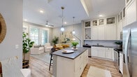 Located at 4310 W Spruce St in Tampa, FL, this thoughtfully designed one-bedroom, one-bathroom residence offers a comfortable and modern living experience across a single floor. The open-concept kitchen and living area serves as the heart of the home, where the kitchen impresses with floor-to-ceiling white cabinetry featuring glass-front upper cabinets, a white subway tile backsplash, gray quartz countertops, stainless steel appliances, and warm wood-look flooring. A central island with seating provides an ideal casual dining spot beneath pendant lighting. The living room is bright and welcoming, with large windows that invite natural light and outdoor views of lush greenery, complemented by a ceiling fan and recessed lighting. The spacious bedroom offers plush carpeting, a ceiling fan, natural light from a well-positioned window, and a serene, neutral palette. A dedicated walk-in closet features multi-level wire shelving for ample storage. The bathroom is finished with a white vanity, gray countertop, large mirror, and a tiled tub-shower combination with stone-look tile flooring, completing this polished and livable Tampa residence.