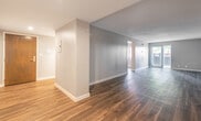 This single-floor unit offers a thoughtfully updated interior with a clean, modern aesthetic carried consistently throughout. The galley-style kitchen is a standout feature, showcasing white shaker cabinetry, white quartz countertops, a white subway tile backsplash, and a full suite of stainless steel appliances including a slide-in range, over-the-range microwave, and dishwasher. A window at the end of the kitchen draws in natural light, enhancing the bright, contemporary feel.

Rich hardwood-style flooring extends throughout the main living areas and bedrooms, providing a warm and cohesive visual flow. The spacious living and dining areas offer generous room to move, with neutral-toned walls and textured ceilings contributing to a clean, understated ambiance.

Multiple bedrooms each feature large windows that invite natural light and offer views of the surrounding greenery. One bedroom includes a double closet with white panel doors, providing practical storage. The neutral color palette across bedrooms lends versatility for various uses.

Two bathrooms serve the unit: one features a soaking tub with elegant marble-style surround walls and chrome fixtures, while the second includes a standalone glass-enclosed shower, a vanity with white cabinetry, and light tile flooring — both finished to a clean, modern standard.