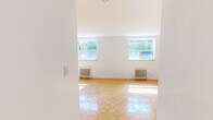 Located at 18 Skipton Crt, Unit 101 in Toronto's northwest end, this single-floor unit offers a thoughtfully arranged layout designed for efficient everyday living. The main living area is a welcoming, open space characterized by warm parquet flooring laid in a classic basket-weave pattern that adds a timeless charm to the interior. Bright white walls keep the space feeling clean and airy, while large windows allow generous natural light to pour in and offer views of the surrounding greenery. A classic cast-iron radiator provides reliable, comfortable heating. The kitchen is well-appointed with crisp white shaker-style cabinetry, grey countertops, a subway tile backsplash, and stainless steel appliances including a refrigerator, stove, and microwave. Light tile flooring in the kitchen complements the overall clean aesthetic. A connecting hallway links the living and kitchen areas, providing functional flow throughout the unit. The space is finished with clean white trim and baseboards throughout, contributing to a cohesive and polished look. Overall, the unit presents a bright, practical, and neatly maintained living environment in a residential Toronto neighbourhood.