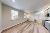Located at 888 Fourth St in Santa Rosa, California, this thoughtfully designed one-bedroom, one-bathroom unit offers a practical and comfortable single-floor layout. The open-concept living, dining, and kitchen area serves as the heart of the space, featuring light-toned wood-style flooring that runs throughout and multiple windows dressed with horizontal blinds, flooding the area with natural light and offering views of surrounding greenery. Neutral, warm beige walls create a clean and cohesive aesthetic throughout.

The bedroom is carpeted for comfort and includes two closets — one a sliding-door closet and an additional separate closet — providing ample storage. Windows in the bedroom allow for natural light and outdoor views, contributing to an airy feel despite the cozy footprint.

A hallway connects the main living areas to the private spaces, maintaining a logical and efficient flow. The bathroom features tile flooring, a shower-tub combination with chrome grab bars and a glass enclosure, a toilet, and overhead cabinetry in a contemporary gray finish, offering functional storage.

A dedicated laundry area is equipped with a stacked washer and dryer unit, adding everyday convenience. The consistent use of neutral tones, natural light, and modern finishes throughout gives this unit a clean, move-in-ready character.