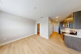 Located at 700 N Second St in Brighton, MI, this efficiently designed studio offers a thoughtfully arranged single-floor layout that maximizes every square foot. The combined kitchen and living area serves as the heart of the space, where a sleek galley-style kitchen showcases dark wood cabinetry, stainless steel appliances including a refrigerator, electric range, and built-in microwave, a undermount sink with modern faucet, and a crisp white herringbone tile backsplash. Light wood-tone flooring runs continuously throughout, lending warmth and a sense of visual continuity. The open living area is bright and airy, benefiting from multiple windows dressed with horizontal blinds that frame views of the surrounding Brighton streetscape and allow generous natural light to fill the room. Neutral gray walls provide a clean, versatile backdrop throughout. The bathroom is well-appointed with a full tub/shower combination, a wood-toned vanity with a white countertop, and brushed nickel fixtures and hardware, maintaining the modern aesthetic found throughout the unit. A dedicated closet provides convenient storage. Recessed lighting and clean white ceilings complete the contemporary, move-in-ready feel of this efficiently planned Brighton studio.