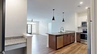 Located in Winston-Salem, NC, this well-appointed 2-bedroom, 2-bathroom single-floor home offers a thoughtfully designed open-concept layout. The combined kitchen and living area serves as the heart of the home, where warm wood-look flooring flows seamlessly throughout. The kitchen is a standout feature, showcasing rich dark lower cabinetry paired with crisp white upper cabinets, a classic subway tile backsplash, granite countertops, and a full suite of stainless steel appliances. A central island with pendant lighting provides additional prep space and a natural gathering point that opens directly into the living area. The living room is bright and welcoming, featuring a glass-paneled entry door with sidelights that invite natural light and outdoor views. The spacious primary bedroom offers plush carpeting, generous closet space, and windows overlooking the surrounding greenery. The second bedroom is equally comfortable, with soft carpet and ample natural light. Both bathrooms are cleanly finished with wood-look flooring and granite vanities. A dedicated laundry room and connecting hallway round out the functional floor plan, making this home as practical as it is comfortable.