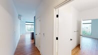 Located in Milwaukee's vibrant lower east side, this modern 2-bedroom, 2-bathroom residence at 1237 N Van Buren St offers a thoughtfully designed single-floor layout with clean contemporary finishes throughout. Warm hardwood flooring flows seamlessly across the entire unit, anchoring the bright, open interior.

The living room is a standout space, defined by expansive floor-to-ceiling windows with sleek black frames that frame sweeping views of the Milwaukee skyline and surrounding cityscape, flooding the room with natural light. The kitchen features modern gray cabinetry, white quartz countertops, white subway tile backsplash, and stainless steel appliances including a full-size refrigerator — all complemented by a wall-mounted mini-split HVAC unit for efficient climate control.

The generously sized primary bedroom enjoys its own city views through large windows, while the second bedroom is equally bright with natural light. Three dedicated closets provide ample storage, including well-organized built-in shelving and hanging systems. Both bathrooms are finished in crisp white with modern vanities and glass-enclosed showers. The unit's minimalist aesthetic, abundant natural light, and panoramic urban views create a polished, contemporary living environment.