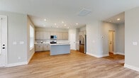 Located at 2762 Lascassas Pike in Murfreesboro, Tennessee, this two-story home offers a thoughtfully designed layout spread across two floors. The main level features an open-concept kitchen and living area with light hardwood-style flooring throughout. The kitchen is well-equipped with gray shaker-style cabinetry, white quartz countertops, stainless steel appliances including a range, built-in microwave, and French door refrigerator, plus a central island with an undermount sink. Large windows on the main floor allow abundant natural light, and a back door provides direct outdoor access. A carpeted staircase with a classic white newel post and wood handrail leads to the upper level, where soaring vaulted ceilings define the spacious primary bedroom, which is filled with natural light from multiple windows. The upper floor also houses the remaining bedrooms, all finished with plush carpet. Four full bathrooms are distributed across both floors, each featuring clean white fixtures. Additional highlights include a dedicated laundry room, five closets for ample storage, two hallways, and an attached garage with an automatic opener and concrete flooring. The home's neutral color palette and modern finishes create a bright, move-in-ready atmosphere throughout.