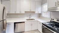 Located at 4811 Monroe Rd. in Charlotte, NC, this single-floor home offers a clean, updated interior with a cohesive design throughout. Rich hardwood floors flow across the living areas and bedrooms, reflecting natural light and lending warmth to the neutral gray walls and white trim.

The open living and dining area is generously proportioned, with windows that invite ample natural light and provide views of the surrounding greenery. The layout connects seamlessly to the kitchen, which features white shaker-style cabinetry extending to the ceiling for abundant storage, bright white countertops, a stainless steel undermount sink with a pull-down faucet, a stainless steel dishwasher, and an electric range.

The bedrooms continue the hardwood flooring and soft gray color palette, each offering closet storage — including a double-door closet in one room. The two bathrooms are finished with light tile flooring and white fixtures. One bathroom includes a walk-in shower stall with a window for natural ventilation, while the second features a full tub-shower combination with white tile surround.

Overall, the space presents a well-maintained, move-in ready interior with consistent finishes and a bright, functional layout throughout.