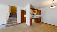 This two-story residence offers a well-organized layout across both levels. The main level centers around a semi-open kitchen, defined by warm oak cabinetry, granite countertops, and a white electric range. A skylight brightens the kitchen interior, while a peninsula counter creates a natural division between the kitchen and the carpeted living area. Ample upper and lower cabinet storage provides practical functionality throughout the space.

The lower level also features a generously sized living area with neutral-toned carpet, textured ceilings, and a pendant light fixture, creating a comfortable and versatile space. A carpeted staircase connects both floors, accompanied by a closet or utility door nearby.

The upper level includes multiple bedrooms, each finished with plush carpet and window blinds that allow natural light and views of surrounding greenery. One bedroom features a sliding-door closet, while another provides direct access to two separate rooms, one of which serves as a full bathroom with a tub. Two bathrooms are present in the home, each equipped with oak vanity cabinetry, light countertops, large mirrors, and tile flooring. Overall, the residence presents a functional and straightforward interior with consistent warm wood tones throughout.
