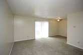 This single-floor residence offers a practical and comfortable layout designed for everyday living. The spacious living area is finished with wall-to-wall beige carpeting and neutral-toned walls, creating a warm, inviting atmosphere. A sliding glass door opens to a private balcony, allowing natural light to fill the room and providing views of the surrounding greenery. The living space connects openly to the kitchen, which features warm wood cabinetry with ample upper and lower storage, white countertops, a tiled backsplash, and white appliances including a refrigerator, dishwasher, and gas range. Durable tile flooring completes the kitchen's functional design. The residence includes multiple carpeted bedrooms, each finished with the same neutral palette. The primary bedroom offers direct access to a bathroom and includes a walk-in closet. Additional bedrooms are served by windows that bring in natural light and feature generous closet space. The full bathroom is clean and well-appointed, with a white vanity, tiled tub-shower combination, and tile flooring. Throughout the home, textured ceilings, white trim, and consistent finishes contribute to a cohesive and understated aesthetic.