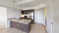 Located on the iconic Monument Avenue in Richmond, Virginia, this single-floor residence combines modern interior design with a classic urban setting. The open-concept kitchen serves as a centerpiece, featuring a large granite-topped island with an undermount sink, dark espresso cabinetry, stainless steel appliances including a refrigerator, range, and microwave, and a tasteful subway tile backsplash. Pendant lighting above the island adds a refined touch to the space.

The living areas are finished with light luxury vinyl plank flooring, while the bedrooms offer plush wall-to-wall carpeting for added comfort. Multiple windows throughout allow natural light to fill each room, with views of the tree-lined surroundings characteristic of Monument Avenue. The bedrooms are generously proportioned, each featuring neutral tones and clean lines.

The unit includes two bathrooms: a full bath with a subway-tiled tub-surround and tile flooring, and a second bath with a granite-topped vanity, dark wood cabinetry, and a large mirror. An in-unit laundry area is also present, adding everyday convenience. The overall aesthetic is clean, bright, and contemporary, offering a comfortable and functional living environment in one of Richmond's most storied neighborhoods.