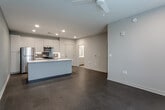 Located at Diamond Parkway in North Kansas City, Missouri, this single-floor unit offers a thoughtfully designed, modern living space with clean finishes throughout. The open-concept kitchen serves as a centerpiece, featuring sleek white cabinetry, a contrasting light blue island with an integrated sink and white countertops, stainless steel appliances including a refrigerator, electric range, and over-the-range microwave, and a tasteful tile backsplash. Recessed lighting illuminates the space, complemented by soft, neutral-toned walls that create a calm, contemporary atmosphere. The flooring in the living and kitchen areas is a durable, low-profile material that flows seamlessly through the space. The bedrooms are generously sized, each finished with plush carpeting, ceiling fans, and windows fitted with horizontal blinds that allow for natural light while maintaining privacy. Views of the surrounding area are visible through the bedroom windows. The bathroom is bright and functional, outfitted with light tile flooring, a white vanity with chrome hardware, grab bars, and clean white walls that lend a crisp, polished look. Overall, the unit presents a well-balanced combination of modern design and practical functionality, making it a comfortable and attractive living space in North Kansas City.