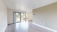 Located in San Diego, CA, this well-appointed one-bedroom, one-bathroom residence offers a thoughtfully designed layout across a single floor. Light-toned luxury vinyl plank flooring flows consistently throughout the space, lending a clean, cohesive aesthetic to every room. The living room is a standout feature, anchored by floor-to-ceiling sliding glass doors that open to a private outdoor area and frame sweeping views of mature eucalyptus trees and natural hillside terrain — a rare backdrop in an urban setting. A ceiling fan and wall-mounted HVAC unit provide year-round comfort. The galley-style kitchen is efficiently arranged with white cabinetry, granite-look countertops, a stainless steel sink, and white appliances including a range and refrigerator, all illuminated by overhead flush lighting. The bedroom is a comfortable retreat with two side-by-side windows offering natural light and garden views, complemented by a large mirrored closet and a dedicated closet with built-in shelving. The full bathroom features a combined tub and shower, a granite-look vanity countertop, and clean white finishes throughout. A hallway connects all rooms, completing this efficient and bright San Diego residence.