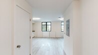 Located at 1698 University Ave in Berkeley, CA, this efficiently designed studio unit offers a thoughtfully organized single-floor layout comprising an open living area, a functional kitchen, a hallway, and a full bathroom. The living space is bright and airy, featuring light-toned luxury vinyl plank flooring, crisp white walls, and black-framed windows that invite natural light and views of the surrounding greenery. Flush-mount ceiling fixtures provide consistent overhead lighting throughout. A dedicated electrical panel is conveniently accessible within the main living area. The kitchen is well-appointed with white cabinetry, a full-size refrigerator, an electric range, a dishwasher, a double-basin sink, and neutral laminate countertops. Open wall-mounted shelving above the counters offers practical storage. The bathroom is clean and accessible, equipped with a full soaking tub and shower combination, stainless steel grab bars along the tub surround and wall, a towel bar, and the same light vinyl flooring carried throughout the unit. The overall aesthetic is clean, modern, and minimalist, making efficient use of every square foot in this well-maintained Berkeley residence.