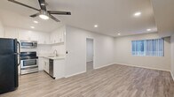 Located on Hillside Avenue in the desirable Hollywood Hills neighborhood of Los Angeles, this 2-bedroom, 1-bathroom unit offers a thoughtfully updated interior with a clean, modern aesthetic. The open-concept living and kitchen area forms the heart of the home, featuring light wood-style laminate flooring, recessed lighting, and a ceiling fan that runs throughout. The kitchen is well-appointed with white shaker cabinetry, light quartz countertops, a stainless steel sink, and a full suite of appliances including a black refrigerator, stainless electric range, over-the-range microwave, and dishwasher. The living area flows seamlessly from the kitchen, offering a bright and versatile space. Both bedrooms are generously sized with neutral gray walls, wood-style flooring, windows with vertical blinds for natural light, and mirrored sliding-door closets for convenient storage. The bathroom is finished with a wide quartz vanity, undermount sink, brushed gold fixtures and hardware, a large mirror, and wood-style flooring that ties the space together cohesively. A hallway connects the main living areas to the bedrooms and bath, keeping the layout functional and efficient. The overall design is clean and contemporary throughout.