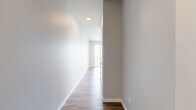 This one-bedroom, one-bathroom unit at 150 Main St in Longmont, Colorado offers a thoughtfully designed single-floor layout with modern finishes throughout. The open-concept living and kitchen area is anchored by warm wood-look plank flooring and a wall of vertical blinds that frame a sliding glass door, flooding the space with natural light and providing access to an outdoor view. The kitchen is well-appointed with two-tone cabinetry in light gray and dark wood, a classic white subway tile backsplash, stainless steel appliances including a refrigerator, range, microwave, and dishwasher, and recessed lighting overhead. The bedroom features a stylish sliding barn door as its entry, soft carpeted flooring, and clean neutral walls, lending a cozy yet contemporary feel. A secondary carpeted room offers flexible use as additional living space or a home office. The full bathroom is finished with large-format tile surrounding a soaking tub and shower combo, wood-toned cabinetry with a white quartz countertop, and coordinating wood-look flooring that ties the space together. Hallways connect each area efficiently, maximizing the functional use of the compact yet well-organized floor plan. The overall aesthetic is clean, modern, and move-in ready.