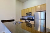 Located at 1200 N Herndon St in Arlington, VA, this two-bedroom, one-bathroom residence offers a thoughtfully designed single-level layout with generous living space. Soaring ceilings throughout create an open, airy atmosphere, while light-toned hardwood-style flooring flows seamlessly from room to room.

The kitchen is a standout feature, equipped with stainless steel appliances including a gas range, microwave, and refrigerator. Rich dark granite countertops complement the warm wood cabinetry, and a peninsula with additional counter space connects the kitchen to the combined dining and living area, making it ideal for both everyday living and entertaining.

The living and dining area benefits from large windows and a glass-paneled entry door that floods the space with natural light. The generously sized primary bedroom features tall ceilings and multiple windows, while the second bedroom mirrors this bright, open feel. Both rooms offer ample closet space — the unit includes five closets in total.

The bathroom is clean and bright, featuring white tile walls, a soaking tub, and mosaic tile flooring. Additional conveniences include a dedicated laundry area and two entrance points. The overall ambiance is modern, clean, and well-lit, presenting a comfortable and functional living environment in the heart of Arlington.