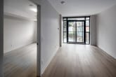Located at 3385 Dundas St W in Toronto's vibrant west end, this thoughtfully designed unit offers a clean, modern aesthetic across a single level of living space. The open-concept kitchen is a standout feature, equipped with stainless steel appliances including a full-size refrigerator, electric range, built-in microwave, and dishwasher. Sleek white cabinetry extends to the ceiling for ample storage, complemented by a subway tile backsplash and a light stone countertop with an integrated sink. Light hardwood-style flooring flows throughout, brightening each room. A dedicated in-unit laundry closet with a stacked washer and dryer adds everyday convenience. The bedroom features large black-framed sliding glass doors that open to a private balcony overlooking a tree-lined neighbourhood streetscape, along with a secondary window that invites abundant natural light. The bathroom is finished with large-format tile flooring, a full soaker tub with shower, and clean white wall surround. Neutral warm-white walls and consistent trim details create a cohesive, contemporary ambiance throughout this well-appointed urban residence.