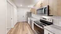 Located on Lakeland Drive NE in Willmar, Minnesota, this efficiently designed single-floor unit offers a clean, modern aesthetic throughout its compact layout. The space includes a living room, kitchen, and full bathroom, all finished with warm wood-look vinyl plank flooring that creates a cohesive and inviting feel.

The kitchen is a standout feature, outfitted with light natural wood cabinetry accented by matte black hardware, a herringbone-patterned tile backsplash, and light gray stone-look countertops. A full suite of stainless steel appliances — including a refrigerator, electric range, over-the-range microwave, and dishwasher — provides modern functionality. Recessed lighting illuminates the kitchen area effectively.

The living room is bright and open, benefiting from a window fitted with white blinds that allows natural light to filter in. A wall-mounted HVAC unit provides climate control. The neutral white walls and clean trim work contribute to a fresh, move-in-ready appearance.

The bathroom features a full-size soaking tub and shower combination with a crisp white surround and chrome fixtures, maintaining the clean and simple design language found throughout the unit. A mirrored vanity and built-in storage round out the space. Overall, this unit delivers a practical and updated living environment with thoughtful modern finishes.