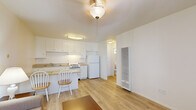Located at 505 W Madison Ave in El Cajon, California, this one-bedroom, one-bathroom unit offers a well-organized single-floor layout designed to maximize every square foot. The living room features light wood flooring, neutral white walls, and two windows that invite natural light and garden views, including a front-facing window with a glimpse of colorful outdoor foliage. A wall-mounted HVAC unit provides climate control, and the open feel of the space makes it comfortable and functional.

The kitchen is efficiently laid out with white cabinetry extending to the ceiling for ample storage, a gas range, full-size refrigerator, and a double-basin sink. Light countertops and a breakfast bar with seating add versatility to the space. Wood-look flooring continues through the kitchen, maintaining visual consistency with the living area.

The bedroom is carpeted for comfort, with a sliding closet and a window overlooking mature trees, providing a calm, shaded view. The room accommodates a standard bed comfortably within its footprint.

The bathroom features a clean, classic design with white tile surrounding the full bathtub and shower, a white vanity with under-sink storage, and a mirrored medicine cabinet above the sink. The overall ambiance throughout is bright, clean, and functional.