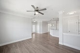 This 830-square-foot, one-bedroom, one-bathroom residence at 2015 Wave Crest Drive in Brentwood, NC offers a well-designed single-floor layout with modern finishes throughout. The open-concept kitchen and living area is anchored by rich, dark-stained cabinetry, granite countertops, and a full suite of stainless steel appliances including a side-by-side refrigerator, electric range, and microwave. Light wood-tone LVP flooring flows through the main living areas, kitchen, hallway, and bathroom, creating a cohesive and easy-to-maintain aesthetic. The living area features crown molding and a pendant light fixture near the entryway, with natural light streaming through front-facing windows. The 200-square-foot primary bedroom is carpeted and includes a ceiling fan, multiple windows with outdoor views, a walk-in closet with built-in wire shelving, and direct access to the full bathroom. The bathroom offers dark wood vanity cabinetry with granite counters and a glass-enclosed shower. A dedicated in-unit laundry room includes a washer and dryer with overhead cabinetry for extra storage. The hallway connects all spaces efficiently, completing this functional and attractive floor plan.