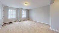 Located at 118 Niagara St in Middletown, Rhode Island, this single-floor unit offers a practical and comfortable layout with multiple rooms spread across a well-organized floor plan. The living areas are finished with neutral-toned wall-to-wall carpeting and light gray walls, creating a clean, understated aesthetic throughout. Multiple windows fitted with vertical blinds allow generous natural light to fill each room, while baseboard heating units provide efficient climate control. The open, unfurnished rooms offer versatile use of space.

The kitchen is a functional highlight, featuring dark espresso cabinetry, light stone-finish countertops, and stainless steel appliances including a gas range, microwave, and dishwasher. Wood-look flooring runs through the kitchen, which opens directly to a private outdoor deck via a sliding glass door — a convenient feature for outdoor enjoyment. The bathroom continues the wood-look flooring and includes a white vanity with ample counter space, a toilet, and a tub/shower combination. The overall ambiance of the unit is tidy and move-in ready, with a straightforward design suited for comfortable everyday living.