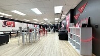 This 2,570 square foot single-floor facility is a comprehensive student recreation center located at 670 University Square, Madison, WI. The space is designed with a modern aesthetic, featuring a black and white color scheme accented by vibrant red, reflecting the University of Wisconsin-Madison's colors. The center is divided into distinct areas to cater to various student needs. A spacious lounge area is furnished with comfortable black sofas and contemporary red metal high-top tables and chairs, creating a relaxed atmosphere for socializing or studying. The fitness section is well-equipped with state-of-the-art cardio machines, strength training equipment, and free weights, all arranged on durable gray carpeting. For entertainment, there's a dedicated gaming area featuring a ping pong table, surrounded by university-themed wall art. The facility also includes a multi-purpose room with colorful murals, likely used for group activities or additional workout space. Bright, recessed lighting and track spotlights illuminate the entire center, while the drop ceiling and HVAC systems ensure comfort. The entrance area showcases purple accent lighting, adding a touch of ambiance. Overall, this thoughtfully designed space offers students a diverse range of recreational options in a stylish, university-branded environment.