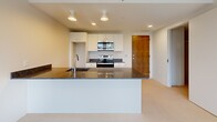Located in the heart of Portland, Maine, this single-floor unit at 120 State St offers a clean, modern design with a thoughtfully laid-out floor plan. The open-concept kitchen serves as a central hub, featuring dark granite countertops, white cabinetry, stainless steel appliances including an electric range and over-the-range microwave, and a large kitchen island with an undermount sink — ideal for both meal preparation and casual dining. Recessed and track lighting illuminate the space effectively.

The living and bedroom areas are carpeted and bathed in natural light through large windows fitted with roller shades, offering views of the surrounding neighborhood. Each room is equipped with a wall-mounted mini-split system for efficient year-round climate control, contributing to the unit's modern, energy-conscious design.

The bathroom is well-appointed with a granite-topped vanity, undermount sink, gray cabinetry with ample storage, and a framed mirror. An in-unit washer is conveniently located within the bathroom area, adding everyday practicality.

Throughout the unit, the clean white walls, light flooring, and contemporary fixtures create a bright, neutral palette that is both inviting and versatile. The overall ambiance is modern and functional, well-suited for comfortable urban living in downtown Portland.