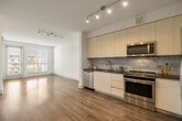 Located on the fifth floor at 6161 Fairmount Ave in San Diego's College Area, Unit 521 offers a thoughtfully designed single-level layout with modern finishes throughout. The open-concept living area features wide-plank hardwood flooring, crisp white walls, and large windows fitted with blinds that invite generous natural light. A track lighting fixture accents the main living space, which flows seamlessly toward a private balcony accessible through a glass door, offering outdoor views of the surrounding neighborhood and tree canopy.

The kitchen is well-appointed with flat-front white cabinetry, dark granite countertops, a marble-style tile backsplash, and a full suite of stainless steel appliances including a side-by-side refrigerator, range, dishwasher, and microwave. Bedrooms are carpeted for comfort and include ceiling fans and large windows. The primary bedroom benefits from a spacious walk-in closet outfitted with wire shelving and dedicated storage. The bathroom features large-format tile flooring, a soaking tub with an overhead shower, marble-style tile surround, and a vanity with ample counter space. An in-unit laundry area adds further convenience to this clean, contemporary residence.
