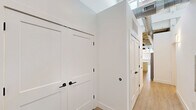 This thoughtfully designed unit in Warrenville, SC, blends industrial character with modern finishes across a well-proportioned single-floor layout. Light wood flooring flows throughout, complementing crisp white walls and matte black hardware that appear as a consistent design thread across every room.

The kitchen is a standout, featuring white shaker cabinetry with ample storage, granite countertops, a classic white subway tile backsplash, and a full suite of stainless steel appliances. Exposed ductwork and industrial pendant lighting add loft-style character, while a peninsula provides additional prep space and opens toward the living area.

The bedroom is bright and airy, benefiting from large grid-pane windows that frame views of the surrounding brick architecture and fill the room with natural light. A ceiling fan adds comfort, and soaring ceilings enhance the sense of openness. A dedicated closet provides practical storage.

The two bathrooms are well-appointed with matching design elements. One features a tub-shower combo with a curved rod, a granite-topped vanity, and dark cabinetry. The second offers a glass-enclosed walk-in shower with subway tile, continuing the cohesive matte black fixture theme. Both bathrooms include wood-look flooring for a seamless aesthetic.

A central hallway with a sliding barn door connects the spaces, reinforcing the unit's modern industrial identity.