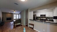 This single-floor, 2-bedroom, 2-bathroom residence in College Station, Texas offers a well-designed layout with a variety of notable architectural and interior features. The living room serves as a central highlight, showcasing vaulted ceilings that create an airy, open feel, a ceiling fan, and a brick wood-burning fireplace flanked by windows that allow natural light to filter in. Wood-style flooring runs through the main living areas, adding warmth and continuity throughout the space.

The kitchen is equipped with stainless steel appliances, including a refrigerator, range, and microwave, complemented by white cabinetry, dark granite countertops, and a mosaic tile backsplash. A breakfast bar connects the kitchen to the dining area, which features a sliding glass door providing outdoor access and additional natural light.

Both bedrooms are carpeted and include ceiling fans and windows. The primary bedroom connects to an en-suite bathroom featuring a dark granite vanity, white cabinetry, and a walk-in closet. The second bathroom includes a tub-shower combination and overhead cabinet storage. A dedicated pantry or storage closet in the kitchen area adds practical utility to the overall floor plan.