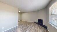 Located in Bedford, TX, this single-story, 3-bedroom, 1-bathroom home offers a practical and cohesive layout designed for comfortable everyday living. Consistent wood-look laminate flooring flows throughout the entire home, creating a unified and easy-to-maintain aesthetic complemented by neutral gray walls and white trim.

The living area is bright and welcoming, highlighted by a corner fireplace with a dark raised hearth and a large window that fills the space with natural light. A secondary living area near the entry also benefits from natural light and provides a versatile flex space. Textured ceilings are present throughout the home.

The kitchen features white cabinetry, light stone-look countertops, and stainless steel appliances including a refrigerator, maintaining a clean and functional workspace. The full bathroom includes a tub/shower combo with white tile surround.

Each of the three bedrooms is equipped with a ceiling fan and light fixture. The spacious primary bedroom connects to a bathroom and includes access to adjacent rooms via a hallway. One bedroom features a built-in closet with sliding doors and a window with outdoor views. All bedrooms carry the same warm, neutral tones found throughout the home, creating a consistent and move-in-ready atmosphere throughout this efficiently designed residence.
