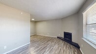 Located in Bedford, TX, this single-story, 3-bedroom, 1-bathroom home offers a practical and cohesive layout designed for comfortable everyday living. Consistent wood-look laminate flooring flows throughout the entire home, creating a unified and easy-to-maintain aesthetic complemented by neutral gray walls and white trim.

The living area is bright and welcoming, highlighted by a corner fireplace with a dark raised hearth and a large window that fills the space with natural light. A secondary living area near the entry also benefits from natural light and provides a versatile flex space. Textured ceilings are present throughout the home.

The kitchen features white cabinetry, light stone-look countertops, and stainless steel appliances including a refrigerator, maintaining a clean and functional workspace. The full bathroom includes a tub/shower combo with white tile surround.

Each of the three bedrooms is equipped with a ceiling fan and light fixture. The spacious primary bedroom connects to a bathroom and includes access to adjacent rooms via a hallway. One bedroom features a built-in closet with sliding doors and a window with outdoor views. All bedrooms carry the same warm, neutral tones found throughout the home, creating a consistent and move-in-ready atmosphere throughout this efficiently designed residence.