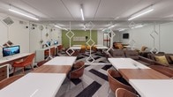 This contemporary single-floor collaborative workspace is thoughtfully designed to support a variety of working and social activities. The layout is divided into distinct yet open zones, seamlessly flowing from one area to the next across a bold, herringbone-patterned carpet in tones of grey, black, and white that anchors the entire space visually.

The workstation zone features a series of clean-lined white and walnut tables paired with modern bentwood chairs in warm brown and burnt orange, offering ample seating for individual work or group collaboration. Desktop computer stations are positioned along one wall, providing additional productivity resources. A wall-mounted flat-screen display is available for presentations or shared viewing.

A lounge area provides a more relaxed setting, furnished with deep brown leather sofas accented with gold patterned throw pillows, alongside a marble-top accent table. Sculptural white geometric diamond-shaped dividers hang from the ceiling, creating a visually dynamic partition between zones while maintaining an open feel.

An accent wall in muted olive green serves as a striking focal point, adorned with an abstract artwork. Glossy yellow spherical ottomans line the base of this wall, adding a playful pop of color. Linear LED lighting illuminates the space uniformly, and the stairwell entry features a bold orange diagonal stripe, reinforcing the space's energetic, modern character.