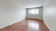 Located at 252 Conacher Dr in Kingston, Ontario, this 2-bedroom, 1-bathroom unit offers a well-organized, efficiently designed layout across a single floor. Warm hardwood-style flooring runs throughout the living areas and bedrooms, complemented by neutral-toned walls and textured ceilings that lend a classic feel to the space. The living room is bright and open, with a large window framing outdoor views and a baseboard heating unit along the wall. Adjacent, the combined dining and kitchen area is a standout feature, showcasing white shaker-style cabinetry with ample storage, a subway tile backsplash, grey laminate countertops, and a full suite of stainless steel appliances including a refrigerator, electric range, over-the-range microwave, and dishwasher. Light tile flooring completes the kitchen's clean, modern aesthetic. The primary bedroom is a comfortable size, featuring a window for natural light and a baseboard heater. The second bedroom includes mirrored sliding closet doors that enhance the sense of space. The unit includes four closets in total, providing generous storage. The bathroom is finished with tile flooring, a white vanity with chrome hardware, and a full soaker tub with shower and a privacy window.