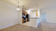 This single-floor residence offers a thoughtfully designed layout that balances functionality and comfort. The open-concept living and dining area is finished with plush wall-to-wall carpeting and features crown molding, a chair rail accent wall, and pendant lighting that adds a warm, inviting ambiance throughout.

The galley-style kitchen is well-equipped with warm wood cabinetry, dark granite countertops, tile flooring, and a full suite of black appliances including a range, microwave, refrigerator, and dishwasher. A breakfast bar provides additional counter space and connects the kitchen seamlessly to the living area.

The bedrooms are carpeted and generously sized, each featuring ceiling fans and windows with blinds that allow natural light to brighten the rooms. The primary bedroom is complemented by a spacious walk-in closet outfitted with multi-tiered wire shelving for ample storage.

Two full bathrooms serve the residence. The primary bathroom includes a standalone shower with sliding glass doors, a vanity with dark granite countertops, and tile flooring. The secondary bathroom features a tub-shower combination with tiled surround, a similarly styled vanity, and matching tile floors. Together, these spaces deliver a clean, cohesive aesthetic throughout the home.