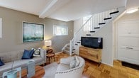 Located in the heart of Los Angeles, this two-story residence at 6200 W 3rd St offers a thoughtfully designed layout across two well-proportioned floors. The main level features a welcoming living room with warm parquet hardwood flooring, exposed ceiling beams, and an abundance of natural light streaming through multiple windows. A staircase with a classic white banister connects the floors, adding architectural charm to the space.

The dining area is bright and inviting, with large windows that frame views of mature trees outside, complemented by a ceiling fan and light-toned tile flooring. The kitchen is outfitted with white cabinetry featuring glass-panel upper doors, granite countertops, a double stainless steel sink, and a gas range, all illuminated by a window overlooking the greenery.

The upper level hosts generously sized bedrooms, each dressed in soft, neutral tones with plush carpeting and ceiling fans. The primary bedroom features multiple windows that bathe the room in natural light and offer serene tree-lined views, while secondary bedrooms include closet space and easy hallway access. Bathrooms feature classic tiled surrounds with tub and shower combinations. Throughout the home, a calm, coastal-inspired palette creates a cohesive and comfortable ambiance ideal for everyday living.