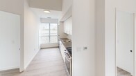 Located at 375 South Street in London, Ontario, this modern 2-bedroom unit offers a clean, contemporary design across a single floor. Light-toned laminate wood flooring runs throughout, complementing the bright white walls and creating a fresh, cohesive aesthetic.

The galley-style kitchen is efficiently laid out, featuring white cabinetry, dark countertops, a stainless steel sink, and stainless steel appliances including a range. A large window at the end of the kitchen draws in natural light and enhances the sense of openness.

Both bedrooms are well-proportioned and filled with natural light through expansive floor-to-ceiling windows that frame views of the London skyline — a standout feature of the unit. The primary bedroom includes a built-in closet with sliding doors and benefits from a tray ceiling detail that adds architectural interest. The second bedroom also enjoys generous window coverage with city and rooftop views.

A connecting hallway provides a logical flow between rooms. Throughout the unit, the design emphasizes clean lines, neutral tones, and abundant natural light, resulting in a bright and airy atmosphere well-suited for comfortable urban living.
