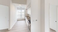 Located at 375 South Street in London, Ontario, this modern 2-bedroom unit offers a clean, contemporary design across a single floor. Light-toned laminate wood flooring runs throughout, complementing the bright white walls and creating a fresh, cohesive aesthetic.

The galley-style kitchen is efficiently laid out, featuring white cabinetry, dark countertops, a stainless steel sink, and stainless steel appliances including a range. A large window at the end of the kitchen draws in natural light and enhances the sense of openness.

Both bedrooms are well-proportioned and filled with natural light through expansive floor-to-ceiling windows that frame views of the London skyline — a standout feature of the unit. The primary bedroom includes a built-in closet with sliding doors and benefits from a tray ceiling detail that adds architectural interest. The second bedroom also enjoys generous window coverage with city and rooftop views.

A connecting hallway provides a logical flow between rooms. Throughout the unit, the design emphasizes clean lines, neutral tones, and abundant natural light, resulting in a bright and airy atmosphere well-suited for comfortable urban living.