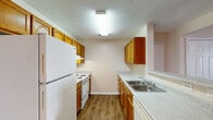 This single-story unit in Pearl, Mississippi, offers a well-organized layout with two bedrooms and two full bathrooms. The living area features rich, dark wood-style flooring, a ceiling fan, and French doors that allow natural light to fill the space, creating a bright and welcoming atmosphere. A textured ceiling adds a classic touch throughout the common areas.

The galley-style kitchen is efficiently designed with warm-toned wooden cabinetry on both sides, light speckled countertops, and wood-style flooring that continues the cohesive look. White appliances, including a refrigerator, electric range, and dishwasher, are provided, along with a stainless steel double sink. Upper and lower cabinetry supply ample storage space.

Both bedrooms are carpeted and offer a comfortable, quiet feel. Natural light enters through windows with blinds, and at least one bedroom includes a closet with a built-in rod for organized storage. The neutral wall tones complement the flooring throughout.

The two bathrooms each feature wood-style flooring, wooden vanity cabinetry, speckled countertops, and a mirror above the sink. One bathroom includes a shower/tub combination, providing practical functionality for daily use.