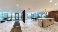 Located at 2030 Hudson St in Fort Lee, NJ, this well-appointed amenity floor offers a thoughtfully designed collection of communal spaces ideal for relaxation, socializing, and recreation. The entry area welcomes residents with striking marble-look tile flooring that extends throughout the main gathering zones, setting an upscale tone from the moment of arrival. Floor-to-ceiling glass walls and expansive windows flood the interior with abundant natural light while offering seamless views of the outdoor terrace, which features pergola-covered seating and open-air lounge areas. The central kitchen and bar area is a standout feature, showcasing a generous white quartz island with sleek bar seating, warm amber pendant lighting, light wood cabinetry, and stainless steel appliances — all complemented by a rich dark wood accent wall. A spacious lounge area with large-format tile and neutral upholstered seating opens directly to the terrace through glass doors, blurring the boundary between indoors and out. A dedicated media lounge features a large wall-mounted television, an oversized sectional sofa, and curated artwork. A cheerful children's playroom with a colorful hexagonal tile floor provides a fun, enclosed space for younger residents. Together, these amenities create a vibrant, multifunctional environment designed for modern community living.