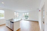 Located at 339 Garden Street in South Burlington, Vermont, this thoughtfully designed two-bedroom, two-bathroom residence offers a clean, contemporary aesthetic throughout its single-floor layout. Warm light wood flooring runs continuously through the space, complementing the crisp white walls and recessed lighting that create a bright, welcoming atmosphere.

The open-concept living, dining, and kitchen area serves as the heart of the home. The kitchen is equipped with white cabinetry, stainless steel appliances including an electric range, microwave, refrigerator, and dishwasher, along with a central island featuring a sink and generous countertop space. Large corner windows flood the living area with natural light and offer views of the surrounding South Burlington neighborhood.

The primary bedroom is generously sized and includes baseboard heating, while the second bedroom benefits from expansive floor-to-ceiling windows on two walls, providing exceptional natural light and neighborhood views. Both bathrooms feature white vanities, full tub/shower combinations, and light wood-style flooring.

Additional conveniences include four closets for ample storage, a dedicated laundry area, and a hallway connecting the private quarters to the main living spaces. The overall design is clean, modern, and move-in ready.