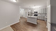 This single-floor residence is designed with a modern, cohesive aesthetic that combines functionality with contemporary style. The open-concept kitchen serves as the heart of the home, showcasing grey shaker-style cabinetry, light granite countertops, and stainless steel appliances including a refrigerator, range, microwave, and dishwasher. A central island with pendant lighting provides additional prep space and a natural gathering point, while wood-look flooring ties the kitchen and adjoining living area together seamlessly.

The bedrooms are carpeted and offer a comfortable, quiet retreat. Each room is equipped with a ceiling fan and features neutral grey walls and clean white trim. One bedroom includes a spacious walk-in closet outfitted with wire shelving and hanging rods for ample storage.

The bathrooms continue the grey and white design theme. The primary bathroom features a dual-sink vanity with granite countertops, grey cabinetry, chrome fixtures, and a large mirror with overhead lighting. A secondary bathroom provides a single-sink vanity with matching finishes and wood-look flooring.

Throughout the space, consistent use of neutral tones, white panel doors, and modern hardware creates a unified and polished look. The layout is thoughtfully organized to maximize both living comfort and storage efficiency.