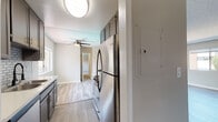 Located at 19143 Victory Blvd in Reseda, CA, this single-floor unit offers a thoughtfully updated interior with a clean, modern aesthetic throughout. The open living and dining area is expansive and bright, featuring light-toned luxury vinyl plank flooring, a textured ceiling, and large windows that invite natural light and outdoor views. A ceiling fan adds both style and function to the space.

The kitchen is well-appointed with dark cabinetry, white countertops, a subway tile backsplash, stainless steel appliances including a full-size refrigerator, and a deep sink with modern fixtures. A window above the sink brings in additional natural light, and the layout offers efficient use of space with ample upper and lower cabinet storage.

A hallway lined with mirrored sliding closet doors connects the main living area to the private quarters, enhancing the sense of depth and light. The bedrooms feature plush carpeting and windows with outdoor views, providing a comfortable and quiet retreat. The bathrooms are updated with stone-finish countertops, dark vanity cabinetry, large mirrors, and a tiled shower-tub combination with a glass sliding door. Wood-look flooring in the bathrooms ties in cohesively with the rest of the unit's design.