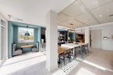 Located at 526 Hartford Tpke in Shrewsbury, MA, this single-floor communal amenity space offers a well-appointed and thoughtfully designed environment spanning just over 1,000 square feet. The layout flows seamlessly between two distinct functional zones, each with its own character and purpose.

The lounge area anchors one end of the space, featuring a teal-accented fireplace wall clad in diamond-patterned tile, flanked by open built-in shelving. Comfortable sectional seating, curated artwork, and decorative accents create a warm, inviting atmosphere. Large glass doors flood the area with natural light and provide views of the outdoor terrace, enhancing the sense of openness.

Transitioning through the space, a dedicated dining zone features a long communal table with mixed seating, suspended over an eye-catching geometric-patterned tile floor. A stylish multi-lamp chandelier anchors the table from above, adding a refined touch.

Adjacent to the dining area, a fully equipped kitchenette serves as a functional hub, outfitted with dark cabinetry, white quartz countertops, a stainless steel sink, a beverage refrigerator, and a dedicated coffee bar station. A large picture window above the sink offers views of the surrounding landscape, bringing in abundant natural light. The coffered ceiling detail, teal accent walls, and light-toned tile flooring unify the entire space with a cohesive, contemporary aesthetic.