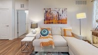 This well-designed 2-bedroom, 2-bathroom single-floor residence offers a thoughtful layout that balances comfort and functionality. The open-concept kitchen is a standout feature, equipped with rich dark cabinetry, stainless steel appliances including a refrigerator, range, and microwave, and a sleek white countertop peninsula with bar seating — ideal for casual dining or entertaining. Warm hardwood-style flooring flows throughout the main living areas, complementing the bright, neutral color palette and recessed lighting overhead. The living area provides a welcoming space with clean lines and an open feel. Both bedrooms are carpeted for comfort, with the primary bedroom offering a ceiling fan, a window with natural light, and direct access to a private en-suite bathroom. The en-suite features a dark wood vanity, white countertops, and stone-look tile flooring. A spacious walk-in closet with dual hanging rods provides generous storage. The second bathroom includes hardwood-style flooring, a dark wood vanity, and a full shower-tub combination. The residence is finished with clean white walls, wide baseboards, and thoughtful details throughout, creating a cohesive and inviting living environment.