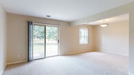 This single-floor, two-bedroom, one-and-a-half-bath residence offers a thoughtfully arranged layout with comfortable living spaces and practical finishes throughout. The combined living and dining area is generously sized, featuring neutral-toned carpet, warm beige walls, and a sliding glass door that opens to a private outdoor deck, framing views of mature trees and greenery. A secondary window further enhances natural light in this open space, which flows into a dedicated dining area illuminated by a pendant light fixture.

The kitchen is equipped with white cabinetry, dark granite-style countertops, a stainless steel double sink, and a dishwasher, with wood-style flooring adding warmth underfoot. Both bedrooms are carpeted and bathed in natural light from multiple windows overlooking the surrounding landscape, providing a calm and inviting atmosphere.

The full bathroom features wood-style flooring, a white vanity with granite countertop, and a shower-tub combination with a window above for natural light. The half bath mirrors the refined aesthetic with a granite-topped white vanity. Throughout, the unit maintains a cohesive, neutral palette that lends itself to a clean and functional living environment.