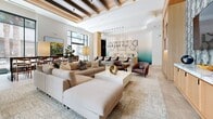 Located at 1140 Harrison St in San Francisco's SoMa neighborhood, this thoughtfully designed single-floor amenity space offers a refined blend of luxury and functionality across a generously sized open layout. The space is divided into two distinct yet cohesive zones, each showcasing high-end finishes and purposeful design.

The main social living area features soaring ceilings with striking exposed wood beam detailing, large-format stone tile flooring, and expansive floor-to-ceiling windows that flood the interior with natural light and offer views of the surrounding urban greenery. This area is anchored by plush, neutral-toned sectional seating, curated artwork, and an elegant marble-accented bar or service counter, creating a warm and inviting atmosphere for gathering.

The screening and lounge wing provides a dramatic contrast with its darkened, intimate ambiance. Rich cognac leather club chairs are arranged in tiered rows facing a large projection screen, complemented by a curved wood-and-marble media console. A three-dimensional geometric accent wall in warm wood tones adds depth and visual interest to the space.

Warm wood paneling, botanical wallcoverings, and carefully layered lighting throughout tie both areas together, resulting in a cohesive, upscale environment ideal for both social events and private relaxation.