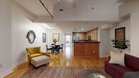 Located on Battery Park Avenue in the heart of downtown Asheville, NC, this well-appointed one-bedroom, one-bathroom residence offers a smartly organized single-floor layout. The open-concept living, dining, and kitchen area serves as the central hub of the home, with warm hardwood floors flowing throughout. The living room features a ceiling fan, distinctive stepped ceiling detail, and a sliding barn-style door, lending a touch of industrial character to the otherwise clean, neutral aesthetic. Large shuttered windows allow for controlled natural light.

The kitchen is equipped with stainless steel appliances, rich wood cabinetry, granite countertops, a mosaic tile backsplash, and a peninsula that opens to the dining and living spaces. The dining area comfortably accommodates a round table and is accented by framed artwork and a decorative mirror.

A bright hallway connects the main living area to the private bedroom, which is generously proportioned and features plush carpet, a ceiling fan, natural light through slatted blinds, and ample room for a desk and seating area. The bathroom offers a white tile floor, a long vanity with double sinks, and a shower-tub combination. A dedicated closet completes this well-rounded residence.