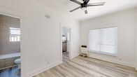 Located at 457 S Witmer St in Los Angeles, CA, this efficiently designed one-bedroom, one-bathroom unit offers a well-organized layout across a single floor. Light wood-style plank flooring runs throughout the space, creating a cohesive and clean aesthetic.

The main living area is bright and open, featuring crisp white walls, a ceiling fan with integrated lighting, and a window fitted with blinds that allows natural light to filter in. A wall-mounted heater provides in-unit climate control. The space flows directly into the kitchen and bedroom areas.

The kitchen is well-appointed with white shaker-style cabinetry, white tile countertops and backsplash, a stainless steel double-basin sink beneath a natural light-filled window, a stainless steel refrigerator, and a black range, offering full cooking functionality.

The spacious primary bedroom features the same wood-style flooring, a ceiling fan, a window with blinds, and a dedicated closet with panel doors — providing ample storage. The bathroom includes a full soaking tub surrounded by large-format beige tile walls and a window for natural ventilation.

This unit combines functional design with clean, modern finishes, making it a practical and well-lit residence in the heart of Los Angeles.