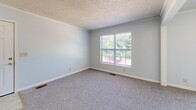 Located at 707 S Washington St in Warrensburg, MO, this single-floor unit offers 2 bedrooms and 2 bathrooms with a functional, well-organized layout. The living room is bright and carpeted, featuring a sliding glass door that opens to a balcony overlooking lush greenery, filling the space with natural light. The galley-style kitchen is efficiently designed with warm wood cabinetry, ample counter space, tile flooring, and a full suite of appliances including a range, refrigerator, and dishwasher. Both bedrooms are carpeted and finished with soft blue-gray walls, crown molding, and windows that frame pleasant outdoor views. The spacious primary bedroom includes a walk-in closet with built-in shelving, providing generous storage. The second bedroom also features a dedicated closet with shelving. Two full bathrooms serve the unit — one includes a standalone glass-enclosed shower with a wood-toned vanity, while the other offers a full bathtub and shower combination. A hallway connects the rooms and includes additional built-in shelving for extra storage. Textured ceilings and crown molding are consistent throughout, contributing to a cohesive, classic feel across the entire unit.
