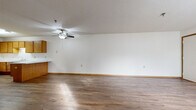 Located at 955 Vadnais Dr in Vadnais Heights, MN, this single-floor, three-bedroom, one-bathroom home offers a practical and comfortable layout. The open living room is a welcoming space featuring warm hardwood-style flooring, a ceiling fan with light fixture, textured ceilings, and neutral white walls with wood-toned baseboards throughout.

The kitchen is well-appointed with abundant warm oak cabinetry providing ample storage, white appliances including a range and refrigerator, a double sink, and light countertops. A peninsula counter connects the kitchen to the living area, creating a functional and social flow between the two spaces.

The three bedrooms feature plush carpeting and natural light from windows with blinds. The primary bedroom is a generously sized retreat, while the additional bedrooms offer closet storage with bi-fold oak doors. Hardwood-style flooring is present in select bedrooms as well.

The bathroom is designed with accessibility in mind, featuring grab bars around the tub-shower combination, an open-concept vanity with a wide mirror, and hardwood-style flooring. The clean, white fixtures and open under-sink design enhance the room's functionality. Overall, the home presents a clean, neutral palette with consistent warm wood accents throughout.